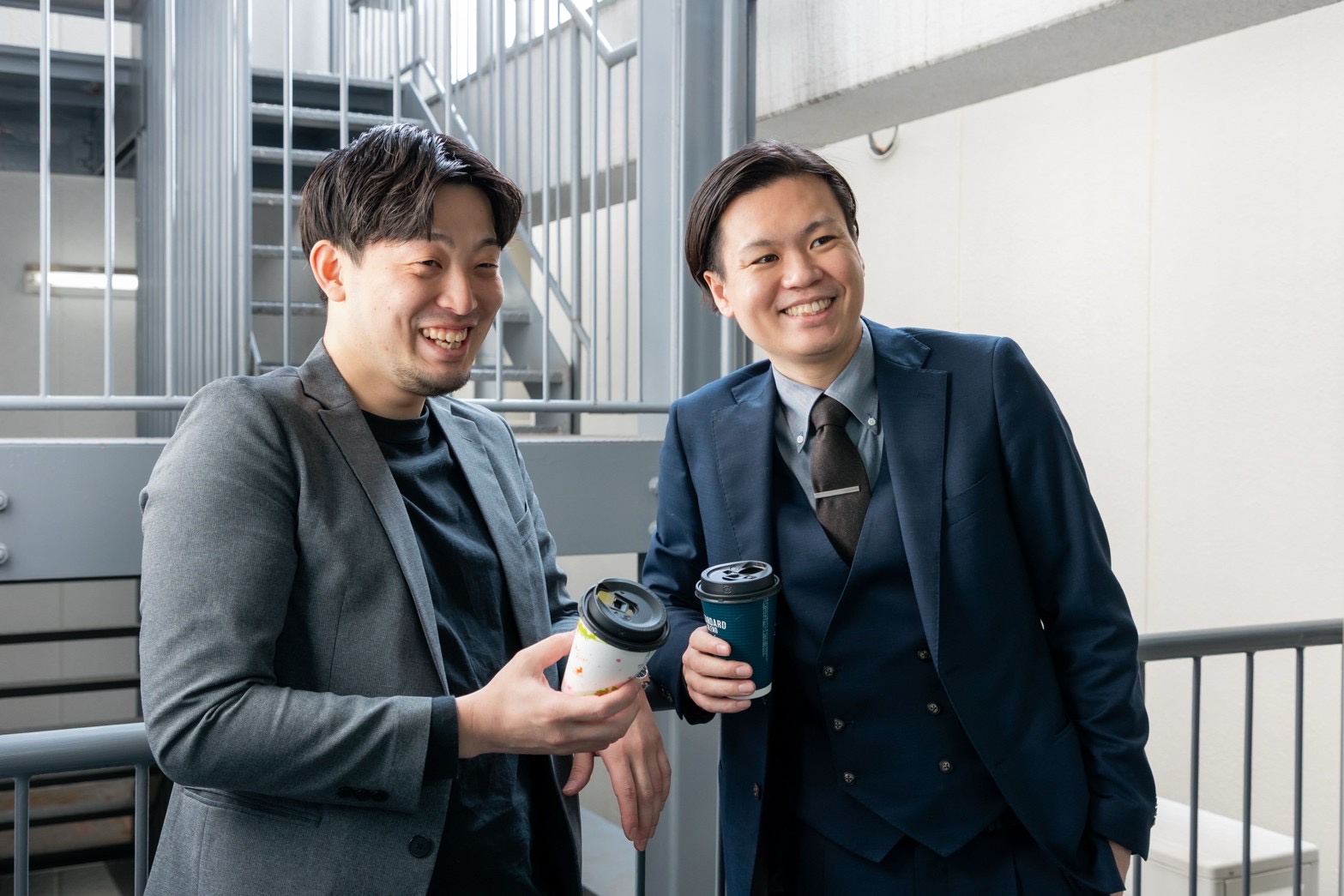 コーヒーを片手に笑い合うBLAYN社員2名